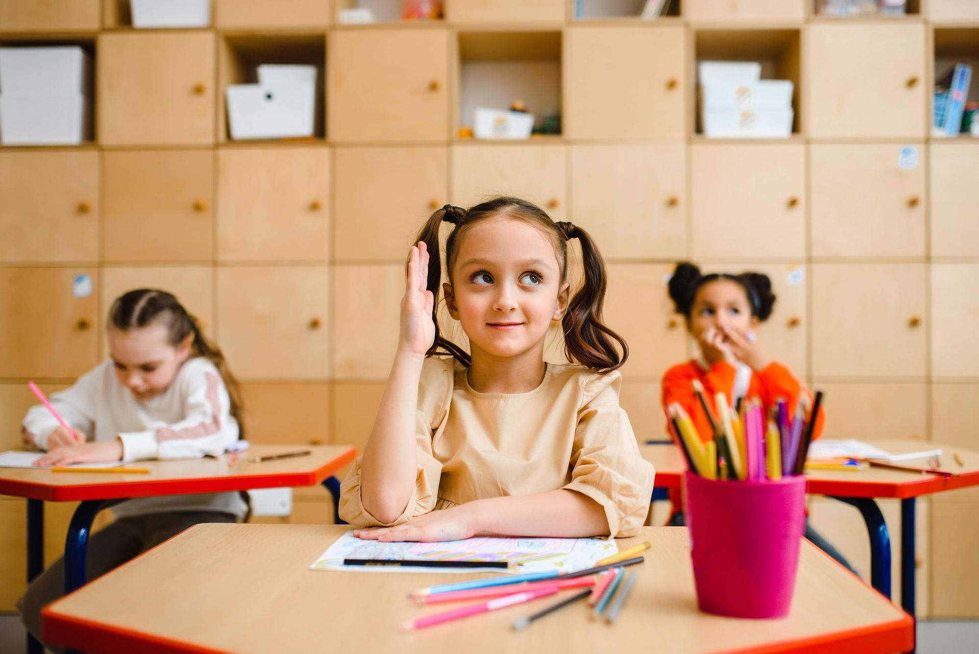 Niña levantando la mano en clase
